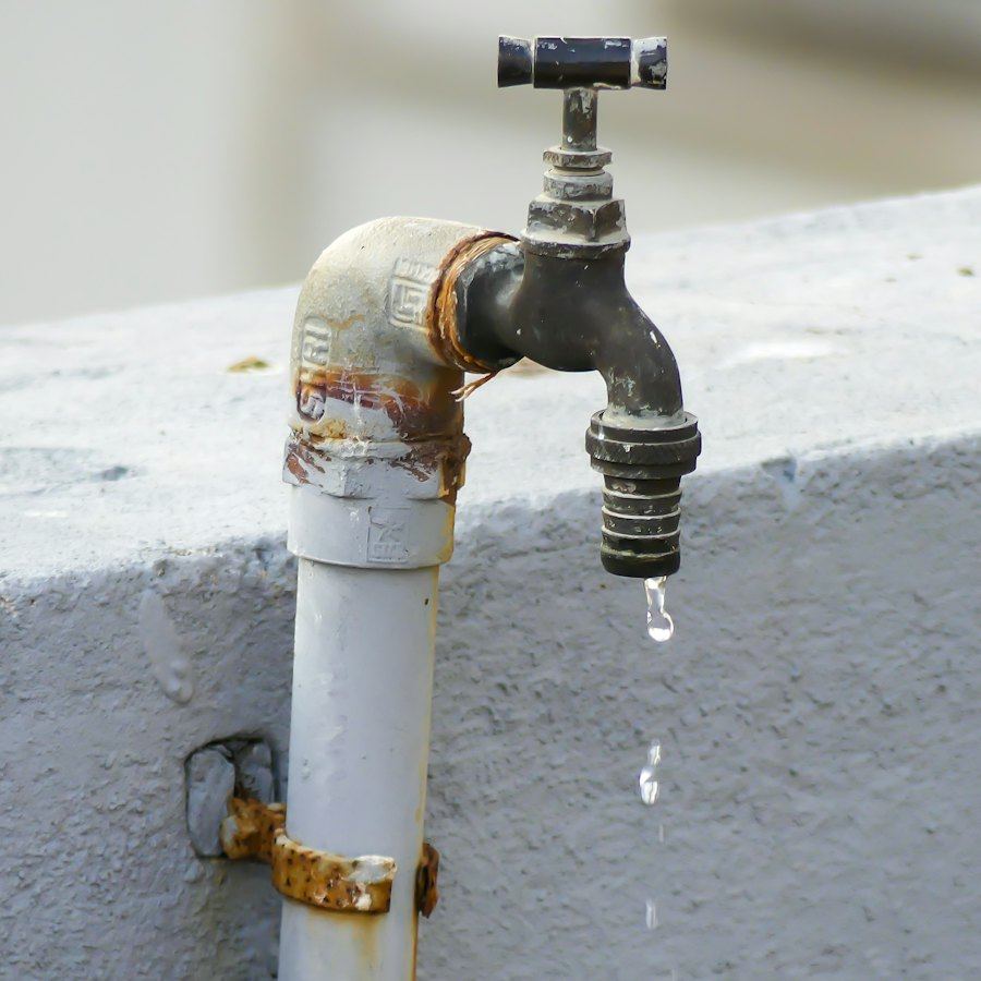 Llave oxidada goteando sobre un muro, detección de fugas de agua en Coquimbo